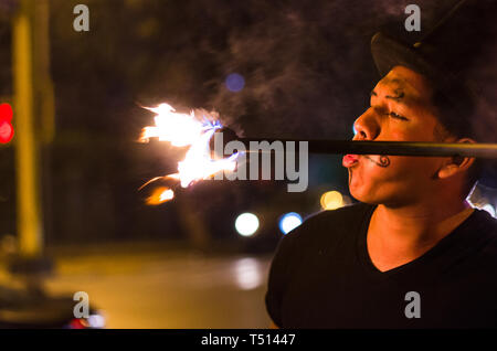 A street artist who makes a show in Lima - Peru, juggling a stick with fire at traffic lights stops, in front of stopped cars Stock Photo