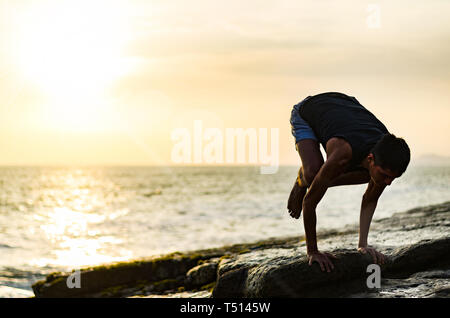 Summer yoga session on a beautiful golden beach of Lima in Peru yoga tour, Bakasana Crow Crane pose Stock Photo