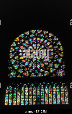 A vertical interior view of one of the three beautiful rose windows in the gothic Notre-Dame de Paris, the famous Catholic cathedral in the French capital that is one of Europe's most popular tourist attractions. This photograph of the large circular stained-glass window was taken before the historic church suffered major damage by a disastrous fire in April, 2019. Rose windows, originally known as wheel windows, depict Biblical scenes or characters in smaller round windows that radiate from the center like wheel spokes or flower petals. Notre Dame's rose windows date to the mid-13th Century. Stock Photo