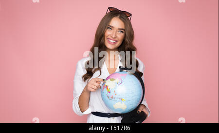 Travel concept. Woman tourist holding globe and pointing on it