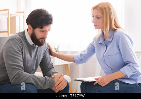 Psychologist comforting sad male patient in office Stock Photo