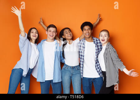 Students having fun over orange studio background Stock Photo