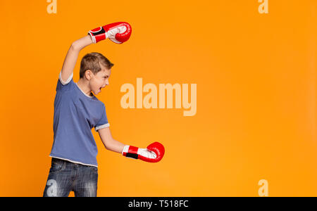 Furious teenager in boxing gloves screaming and attacking Stock Photo