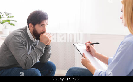 Depressed man getting psychological treatment at clinic Stock Photo