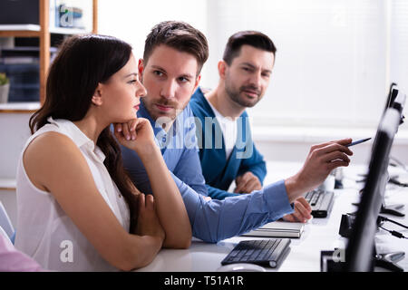 Businessman Pointing On Computer Screen While Talking With Her Colleague Stock Photo