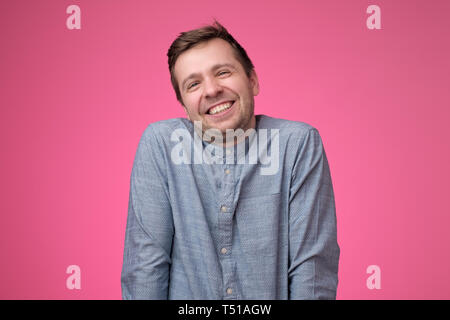 Handsome young man laughing on pink background Stock Photo