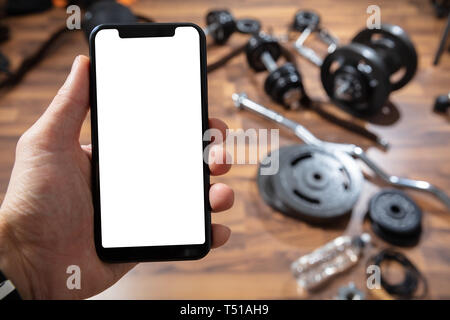 Close-up Of Person's Hand Holding Cellphone With Blank Screen In Gym Stock Photo