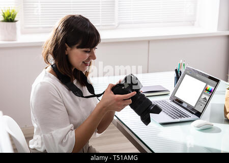 Close-up Of An Editor Looking At Photograph In DSLR Camera At Workplace Stock Photo