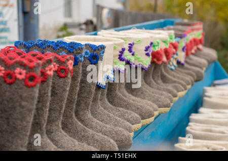Various Slippers, shoes, boots made of sheep wool are on sale at the village counter Stock Photo
