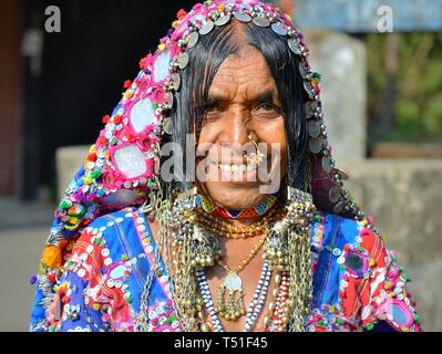 Elderly Indian Lambani tribal woman from Karnataka (Banjara woman, Indian gypsy) with traditional chin tattoos and nose jewelry smiles for the camera. Stock Photo