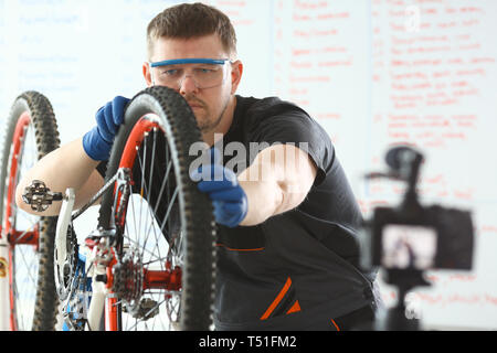 Caucasian Young Man Repairing Bicycle at Workshop Stock Photo