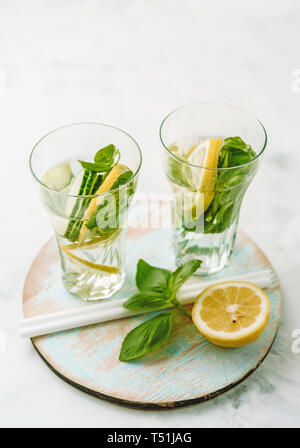 Infused water in two glasses with lemon, cucmber and basil Stock Photo