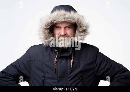 Mature caucasian man with beard in winter jacket with hood. Stock Photo