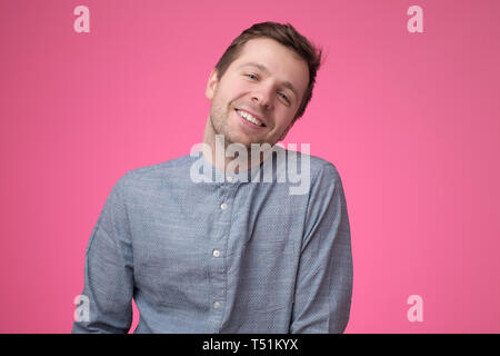 Handsome young man laughing on pink background Stock Photo