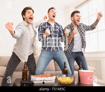 Celebrating victory. Happy football fans watching soccer on tv Stock Photo