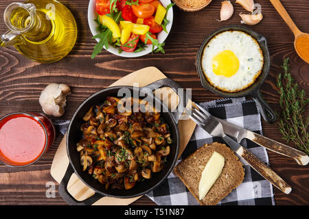 Fried mushrooms and egg in cas-iron skillet. Ingredients for rustic simple food, view from above. Stock Photo