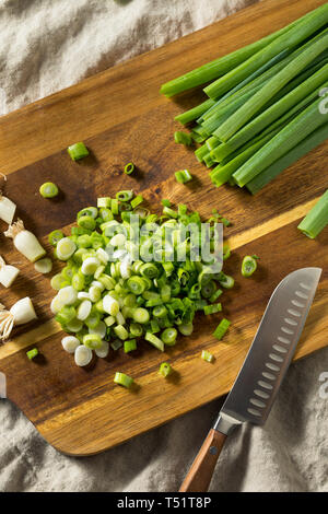 Cutting organic green onions on a wood cutting board Stock Photo - Alamy