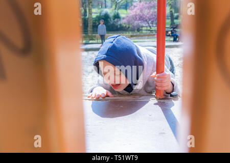 Defect,childcare,medicine and people concept: Blond boy with down syndrome playing in a park.