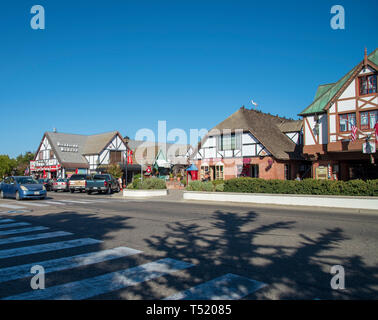 City street with cars and businesses under bright blue sky in small town. Stock Photo
