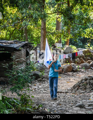 young latin child walking holding flag in Guatemalan village Stock Photo