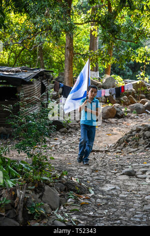 young latin child walking holding flag in Guatemalan village Stock Photo