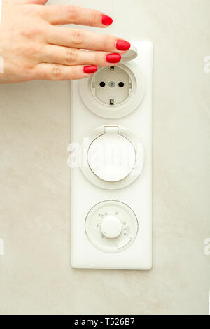 Female hand lifts the protective cover on the electrical outlet. Stock Photo