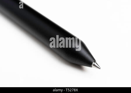 A macro product shot with selective focus of a modern matte finish black clicker barrel ballpoint pen artfully set on a plain white background. Stock Photo