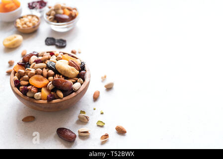 Mixed nuts and dried fruits in wooden bowl on white background, copy space. Healthy snack - mix of organic nuts and dry fruits. Stock Photo