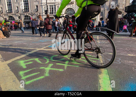 Environmental activist graffiti on the streets of Piccadilly Circus by Extinction Rebellion as the public go by Stock Photo
