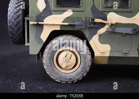 Russian military armored camouflage jeep Tiger. Closeup view. Plastic scale model on dark background. Rear wheel Stock Photo