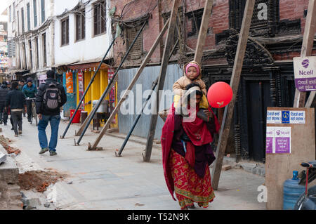 Kathmandu, Nepal - January 21, 2016: Poor woman walks carrying her child in Basantpur. Stock Photo