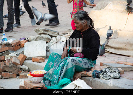Kathmandu, Nepal - May 02, 2017: An old lady selling grains for the pigeons at Kathmandu Durbar Square. Stock Photo