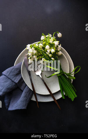 Feastive table setting for holiday Easter dinner decorated with spring snowdrop flowers on rustic table with copy space Stock Photo