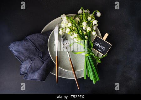 Feastive table setting for holiday Easter dinner decorated with spring snowdrop flowers on rustic table with copy space Stock Photo