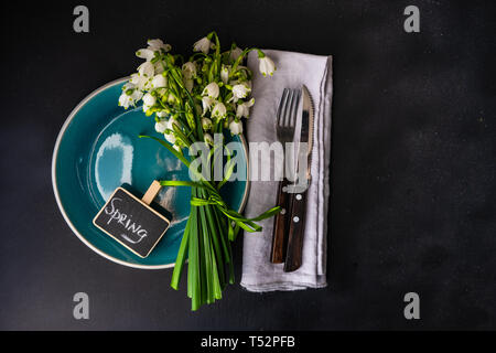 Feastive table setting for holiday Easter dinner decorated with spring snowdrop flowers on rustic table with copy space Stock Photo