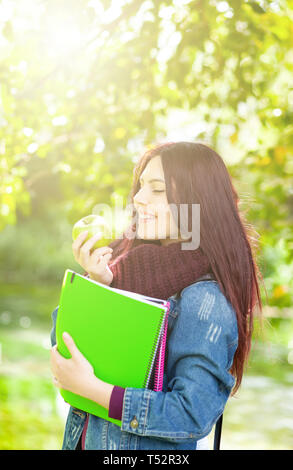 Portrait of beautiful female student holding an green apple. Stock Photo