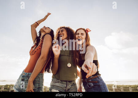 Group of diverse female friends dancing outdoors. Three women having a great time on their summer holidays. Stock Photo