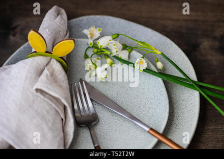 Feastive table setting for holiday Easter dinner decorated with spring snowdrop flowers on rustic table with copy space Stock Photo