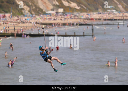 A person takes a ride on a zip wire from the pier to the beach in Bournemouth, Dorset, as Britain is set for a sunny Easter bank holiday weekend, that could break national records. Stock Photo