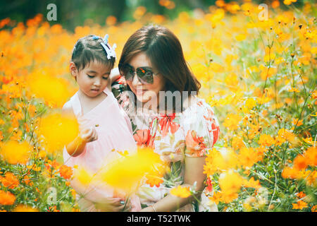 asian woman and little girl happiness emotion in yellow cosmos flower blooming field Stock Photo
