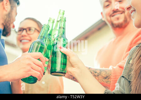 Happy friends toasting beers outdoor - Young people having fun cheering and drinking alcohol at rooftop - Friendship, youth, lifestyle concept Stock Photo