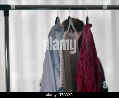 Clothes hanging on hangers, blurred background Stock Photo