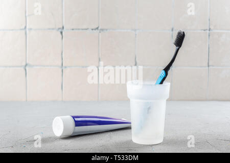 Toothbrush in the bathroom and toothpaste against the wall with ceramic tiles Stock Photo