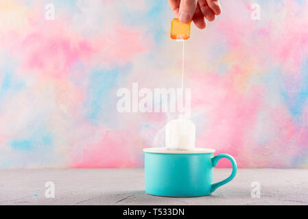 Brewing a tea bag in a cup with a bright color background Stock Photo