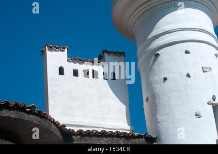 Beautiful plastered with white stucco chimney and tower on the roof of an old house on blue sky background Stock Photo