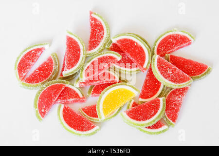 Sweet sugar marmalade in the form of slices of watermelon and lime lies on the white surface of the store counter. Stand out from the crowd. Dessert. Stock Photo