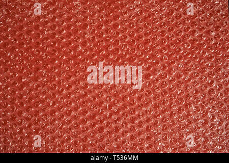Bubble wrap on a red background. Texture and background. Packing bubble film. Stock Photo
