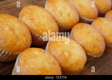 Golden cupcakes lie on a wooden surface of pine boards. Tasty and healthy food. Diagonal perspective and shallow depth of field. Daylight. Close-up Stock Photo