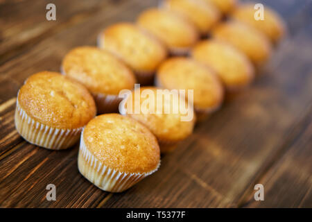 Delicious golden cupcakes on a wooden surface of pine boards. Tasty and healthy food. Diagonal perspective and shallow depth of field. Daylight. Stock Photo