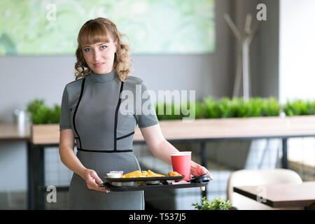A woman of 30-35 years old is holding in her hands a dressing on which juice is water food sushi rolls french fries Stock Photo